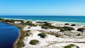 Paisagem costeira com praia, dunas e um corpo de água.