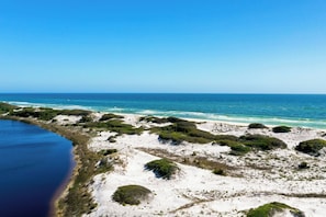 Eine Küstenlandschaft mit Strand, Dünen und einem Gewässer.
