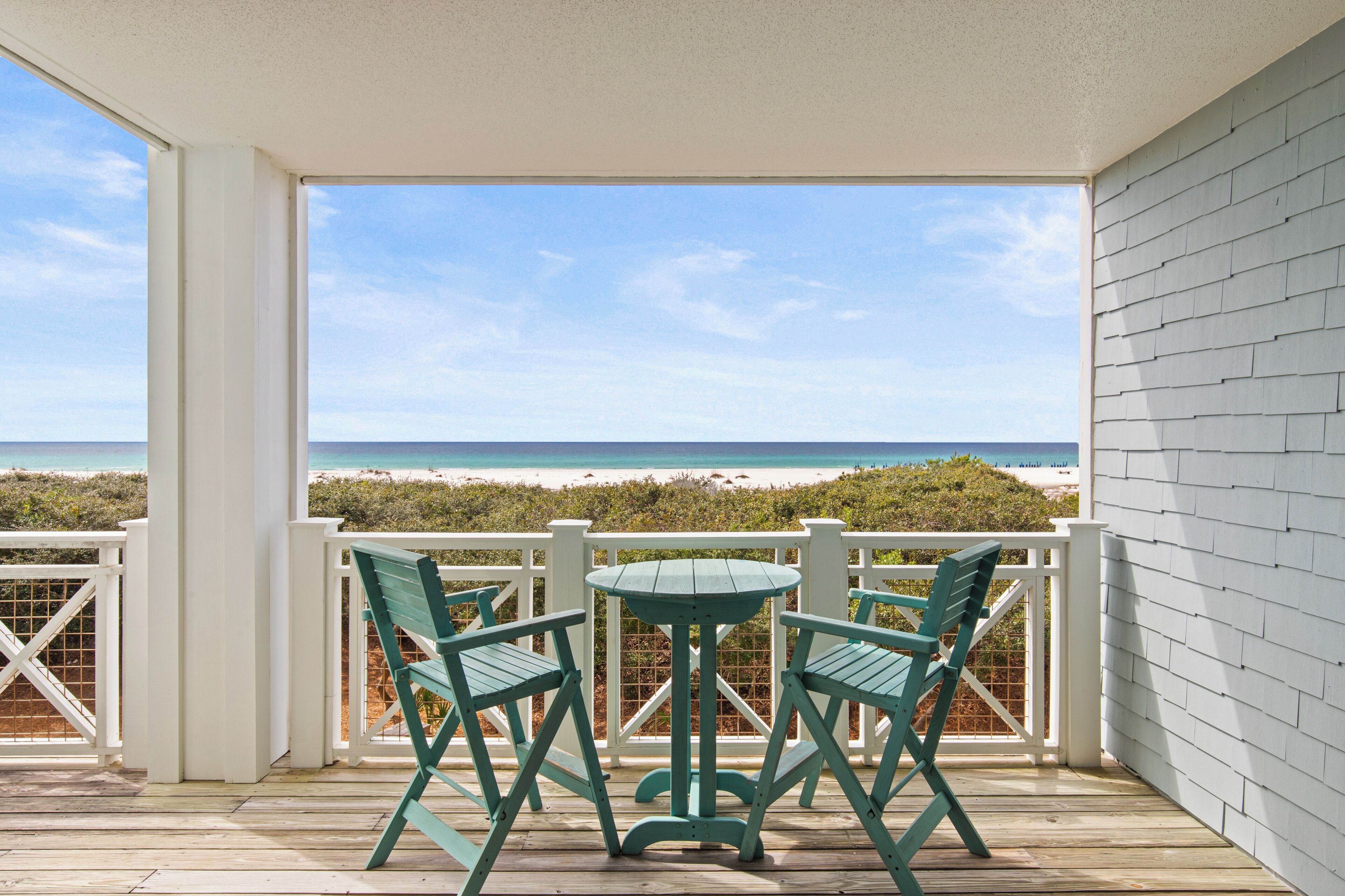 Un espace extérieur abrité, avec une table et des chaises, donnant sur une plage.