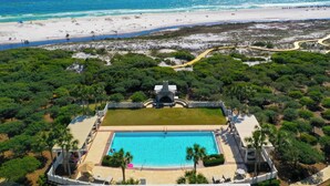 Vista aérea de um resort com piscina, acesso à praia e vegetação exuberante.