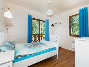 Ein Zimmer mit einem Bett, einem Schminktisch, einem Schreibtisch und einem Fenster mit Vorhängen.