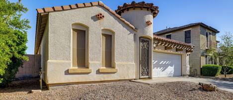 A house with a garage, a stone facade, and a gravel driveway.