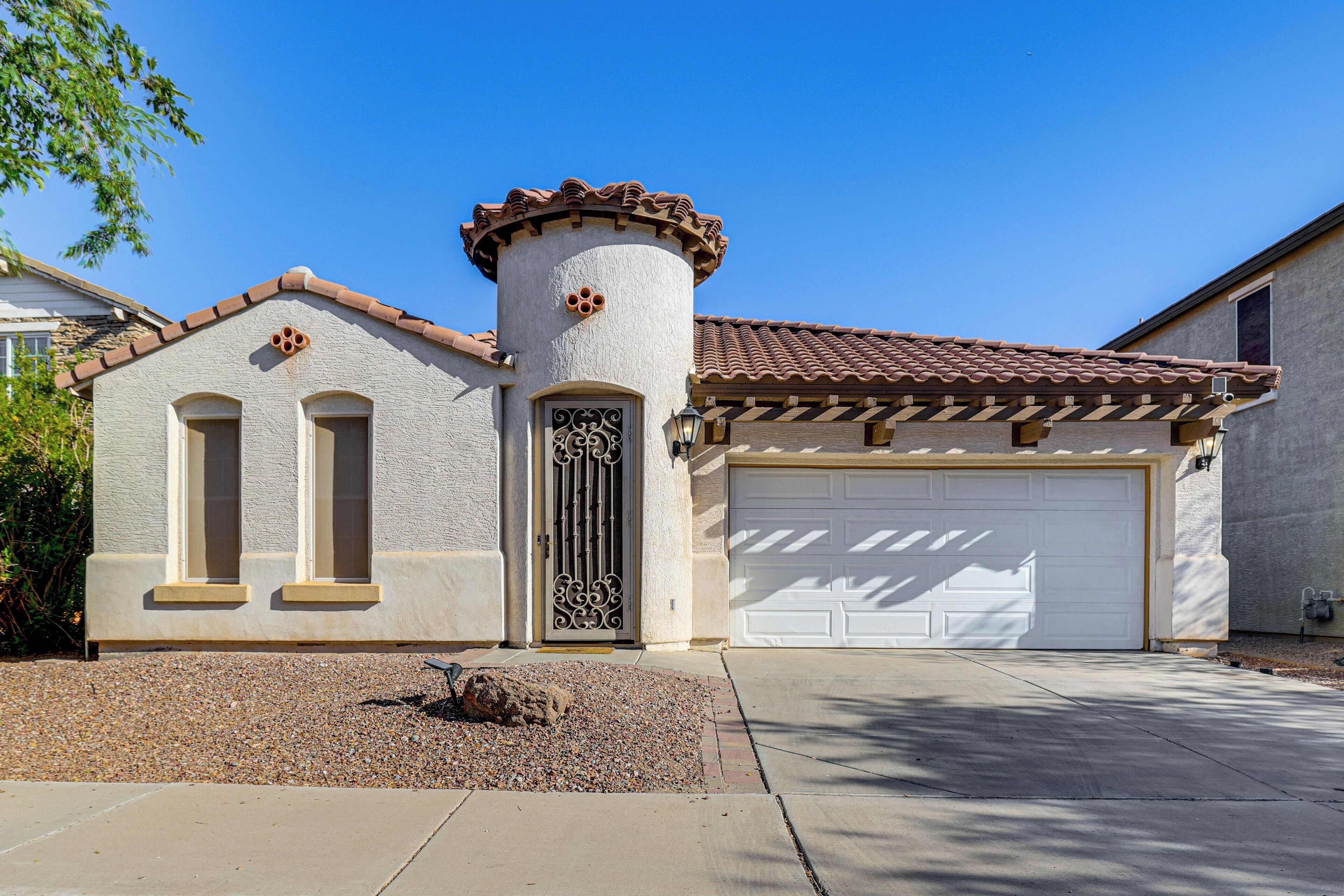 A residential building with a garage, a decorative tower, and a driveway.