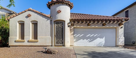 A residential building with a garage, a decorative tower, and a driveway.