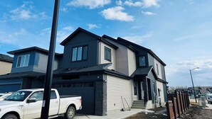 A two-story residential building with a garage, a driveway, and a street view. - Serene Modern Suite | 2BR, Trail & Nearby Lake (Spruce Grove)