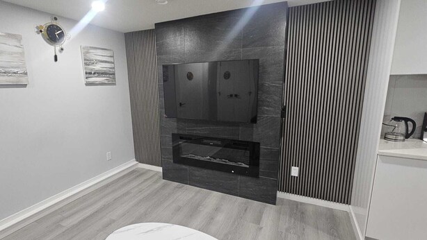 A modern kitchen with a built-in oven, a microwave, and a stove. There are two framed pictures on the wall and a clock. - Serene Modern Suite | 2BR, Trail & Nearby Lake (Spruce Grove)