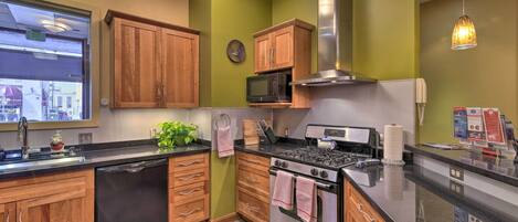 Une cuisine avec des meubles de rangement en bois, une cuisinière en acier inoxydable, un four à micro-ondes et un évier.