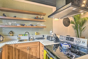 A modern kitchen with wooden cabinets, a stainless steel range hood, a built-in oven, and a countertop with various kitchen items. - Dtwn Anchorage Getaway: 2 Adjoining Condos! (Anchorage)