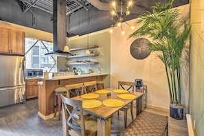 A modern kitchen with wooden cabinets, a central island, and a dining area with a brick floor. - Dtwn Anchorage Getaway: 2 Adjoining Condos! (Anchorage)