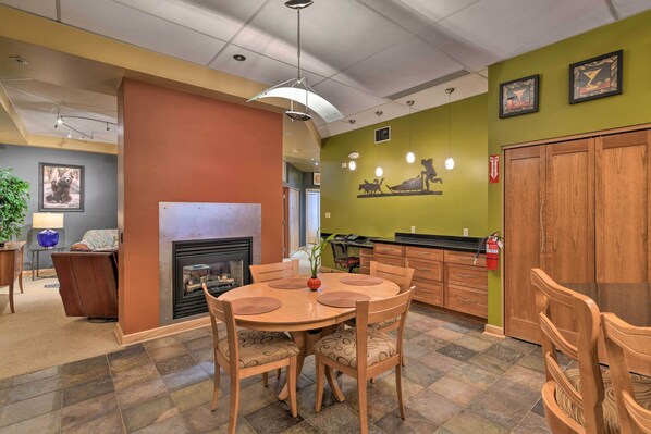 A dining area with a round table and chairs, a fireplace, and a kitchen area with wooden cabinets and a green wall. - Dtwn Anchorage Getaway: 2 Adjoining Condos! (Anchorage)