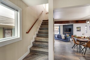 A staircase leading to a living area with a fireplace, a dining table, and a sofa. - Quiet Anchorage Home: Near Parks, Hikes & Airport! (Anchorage)