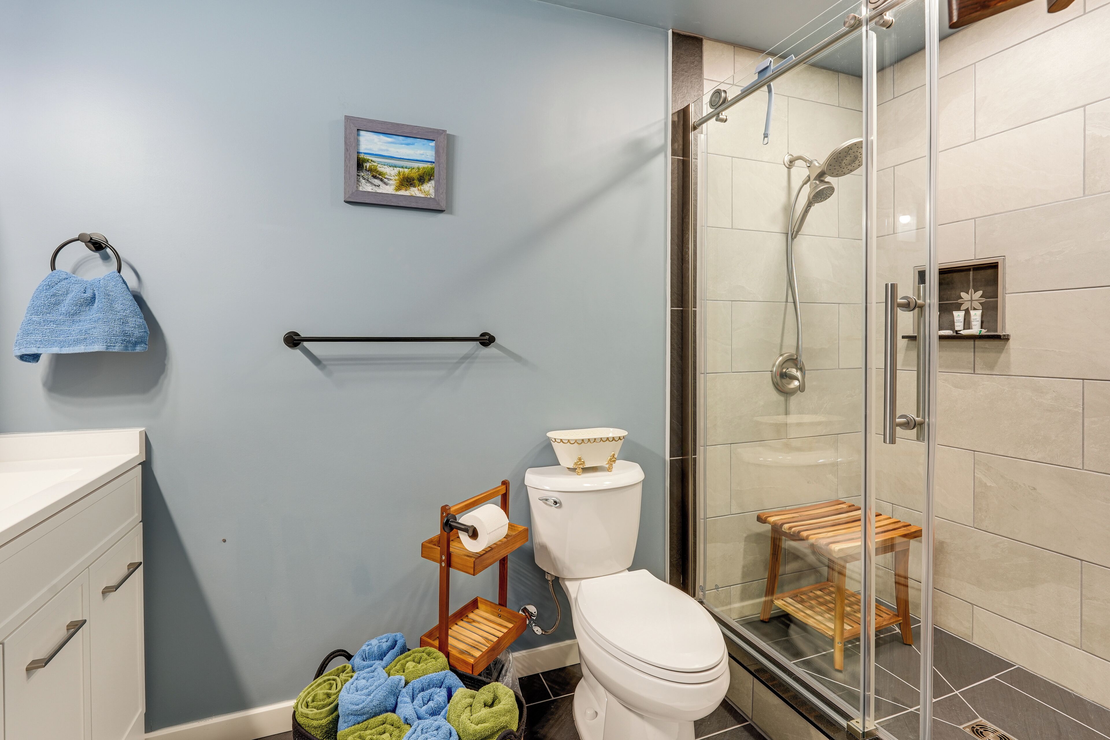 Une salle de bain équipée de toilettes, d’une douche, d’un porte-serviettes et d’une petite étagère.