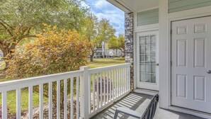 A covered porch with a white railing, a stone wall, and a white door. - Family Favorite 1st Floor Pool Golf (Myrtle Beach)