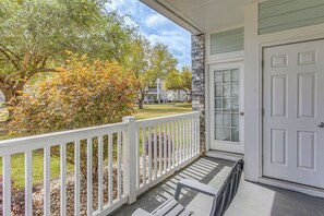 A covered porch with a white railing, a stone wall, and a white door. - Family Favorite 1st Floor Pool Golf (Myrtle Beach)