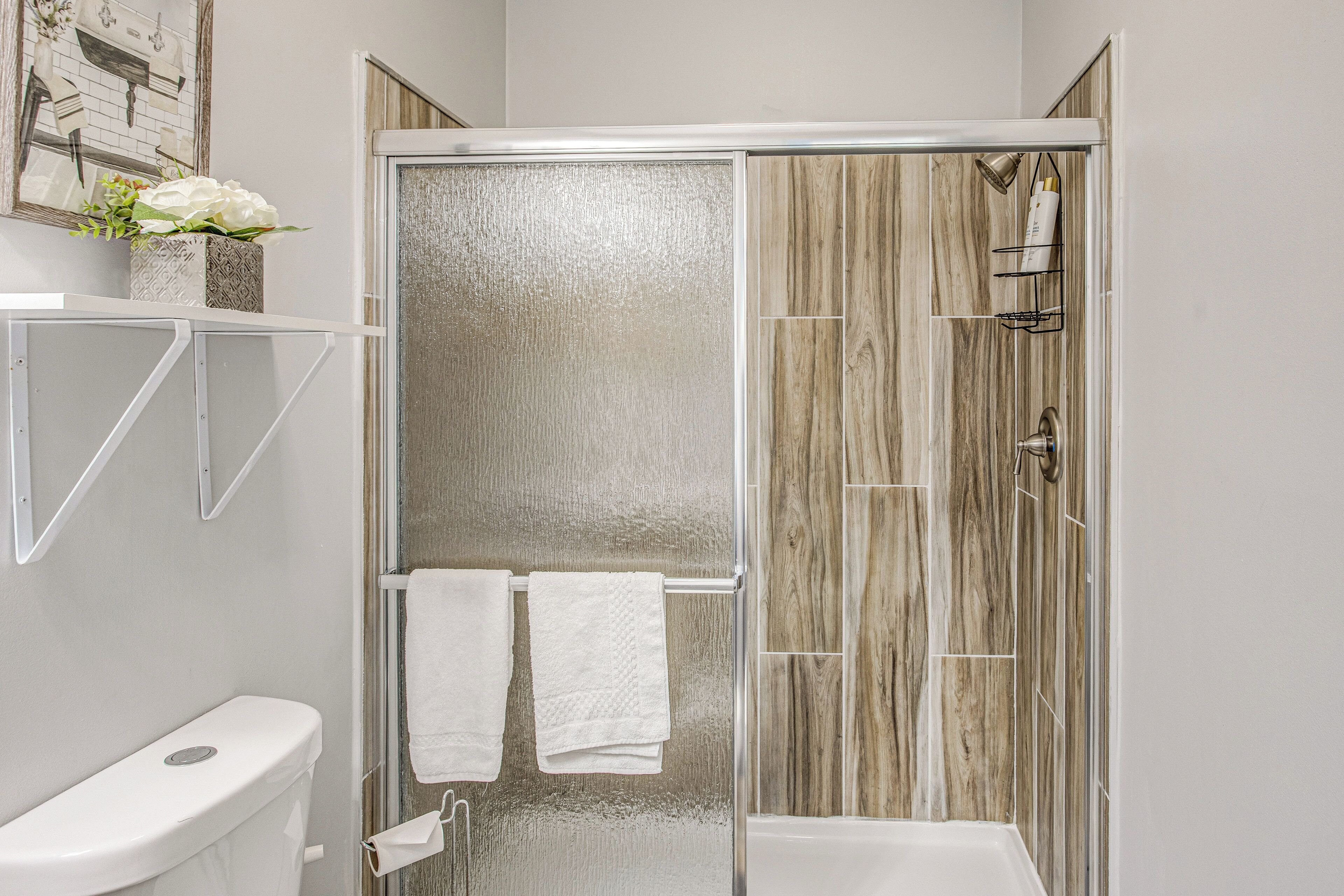 A modern bathroom with a glass-enclosed shower, a toilet, and a sink.