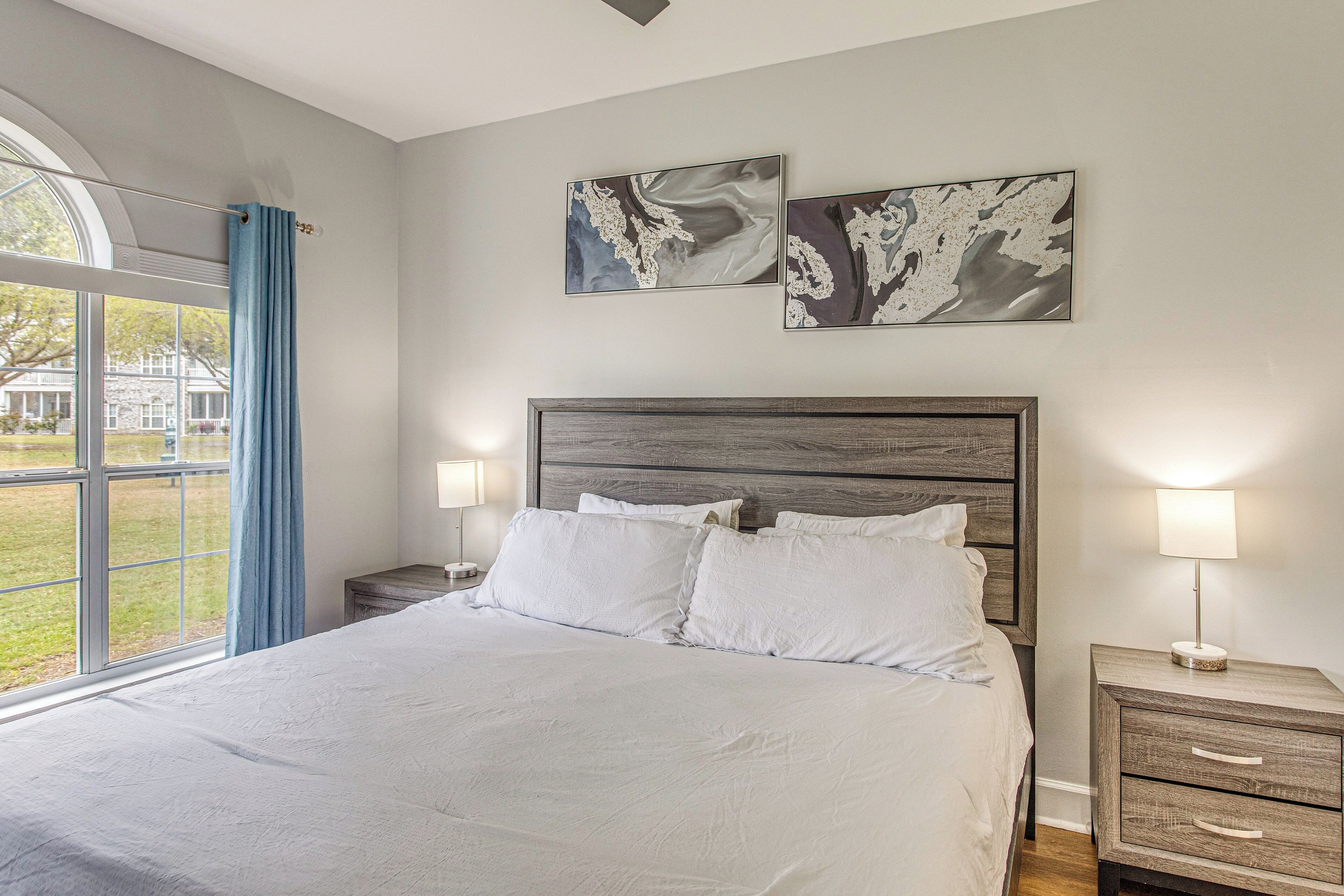 A bedroom with a large bed, two bedside tables with lamps, and abstract art on the wall.