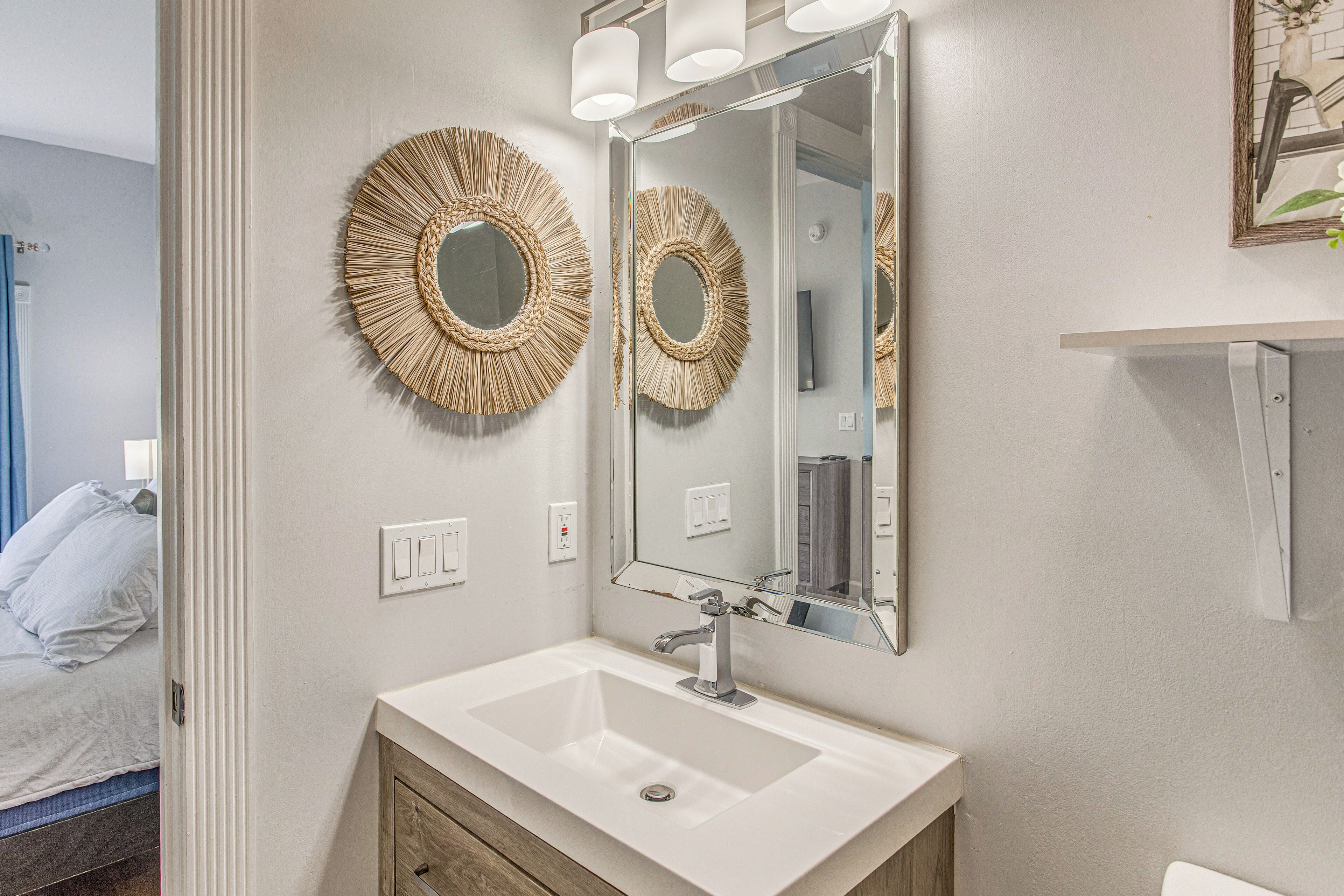 A bathroom with a white sink, a mirror, and two wall-mounted sconces.