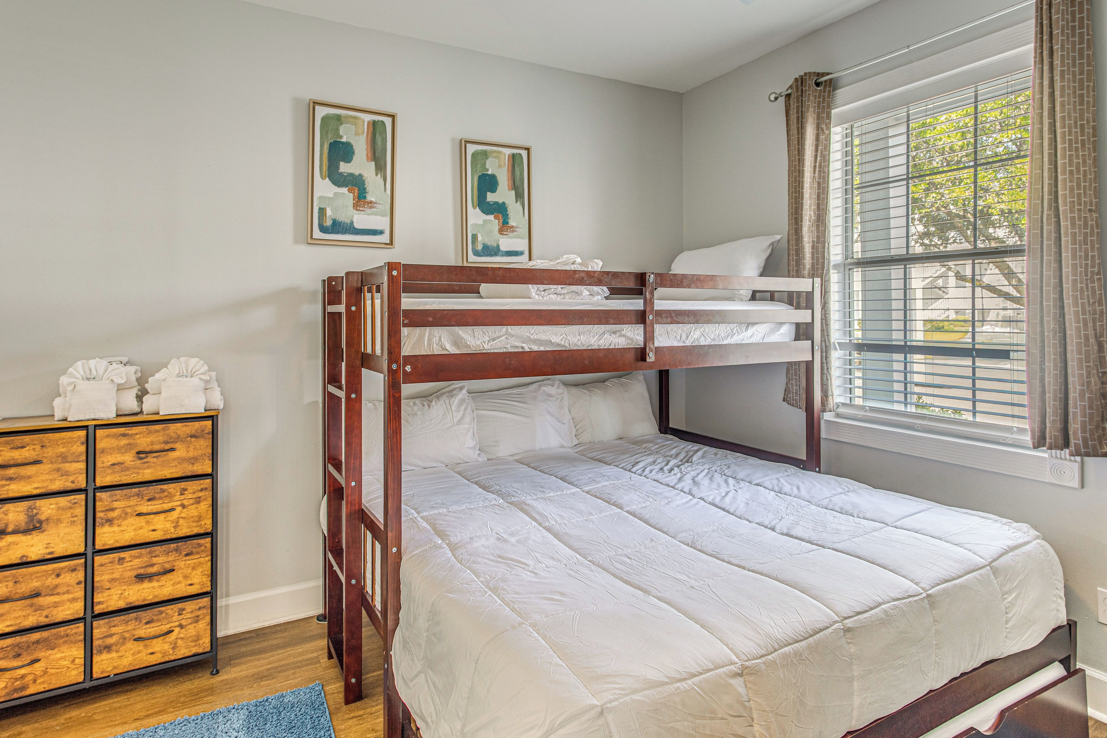 Una camera con un letto a castello, una cassettiera in legno e due quadri appesi.