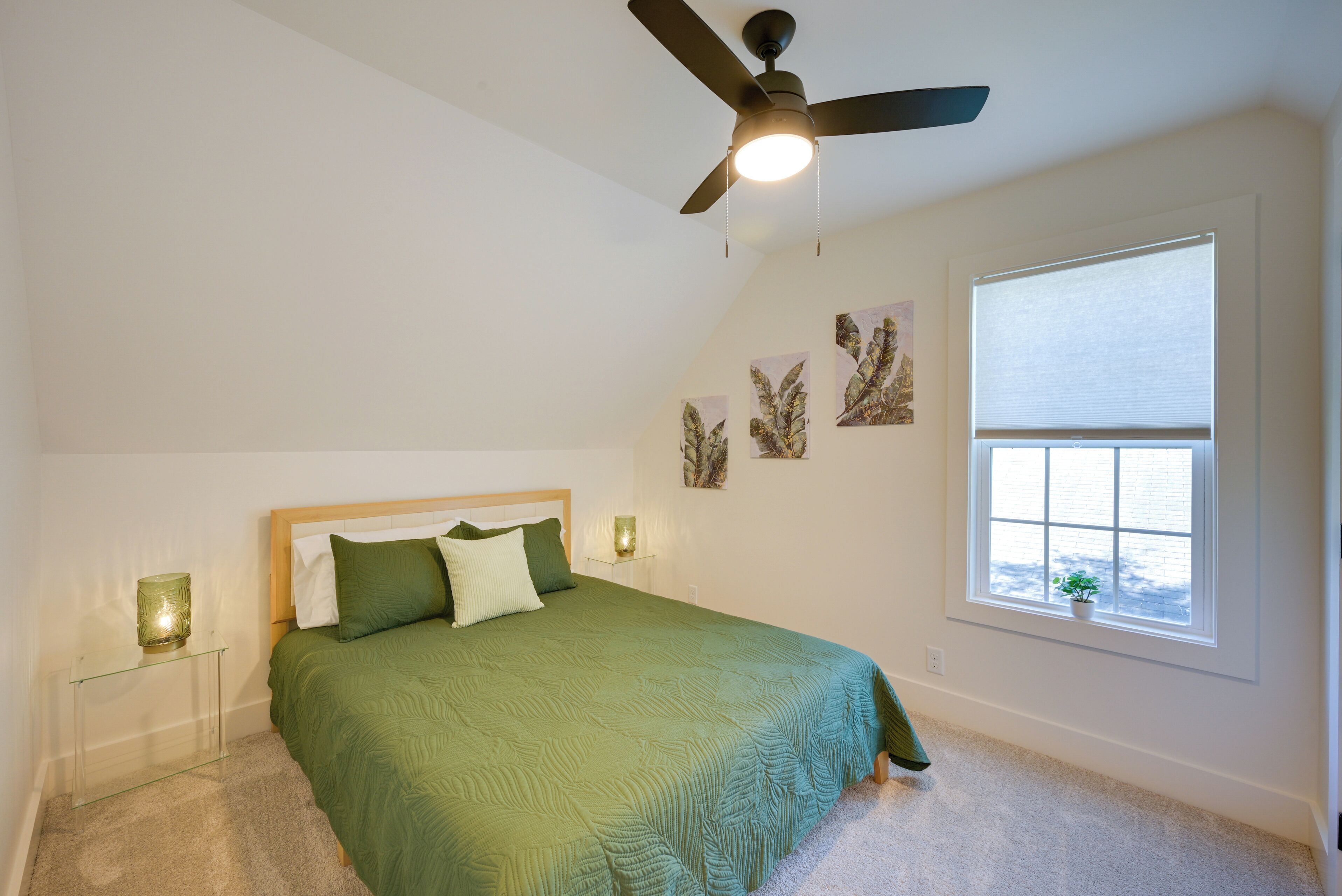 A bedroom with a bed, a ceiling fan, a window with blinds, and wall art.