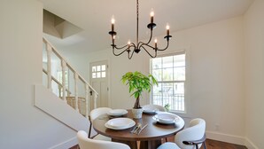 A dining area with a chandelier, white chairs, a round table, and a potted plant. - 5 Mi to Pier Village: Coastal Jade Cottage (St. Simons Island)