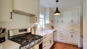 A kitchen with white cabinets, a stainless steel stove, and a wooden floor. - 5 Mi to Pier Village: Coastal Jade Cottage (St. Simons Island)