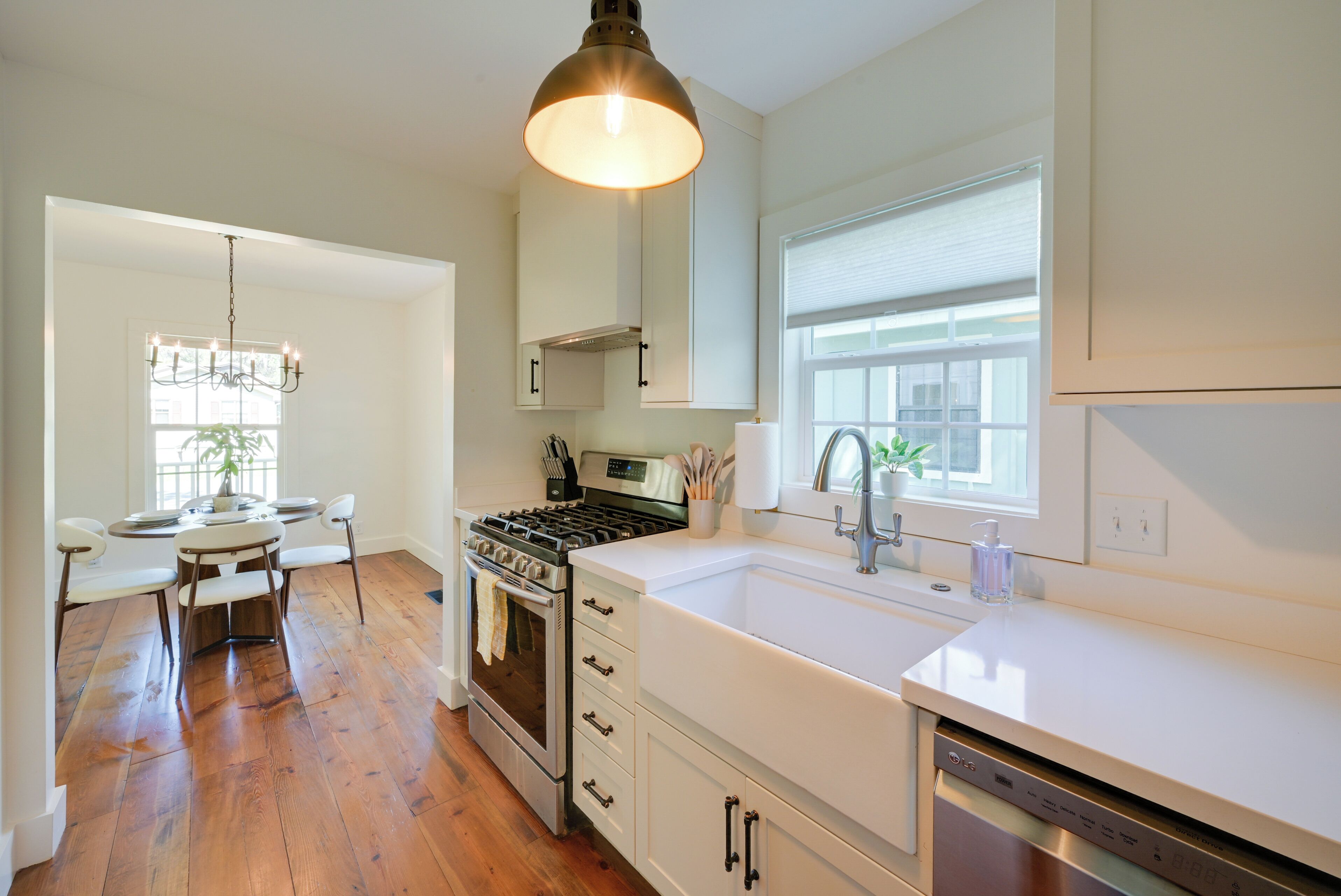 A modern kitchen with white cabinetry, a stainless steel stove, and a large window.