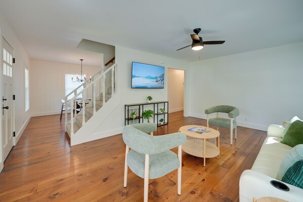 Un salon moderne avec un escalier, une table basse ronde en bois et deux fauteuils rembourrés.