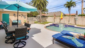 Un jardin avec une piscine, du mobilier d’extérieur et un bar de style polynésien.
