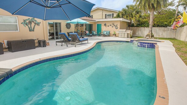 Une piscine à bord incurvé, des chaises longues et un patio couvert.