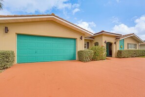 A residential house with a turquoise garage door, a small front porch, and a well-maintained lawn. - Steps to Sand! Singer Island Getaway w/ Bikes (Singer Island)