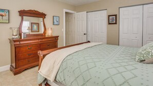 Une chambre à coucher comprenant un lit, une commode, un miroir et deux portes.