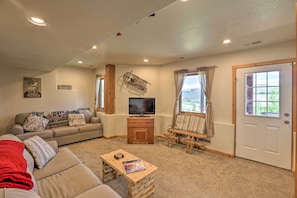 A living room with a sofa, television, wooden coffee table, and a door leading to a balcony. - 2 Mi to Granby Ranch: Granby Home w/ Hot Tub! (Granby)
