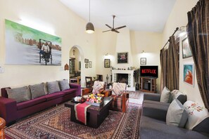 Uma sala de estar com sofá, poltronas, mesa de centro e lareira.