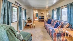 A cozy living room with a sofa, a television, and a dining area with a table and chairs. - 2 Mi to Midtown! All-season Base w/ Hot Tub Access (Ruidoso)