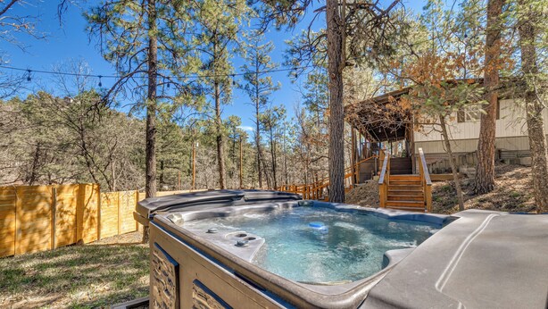 A hot tub in a wooded area with a wooden deck and a staircase leading to a building. - 2 Mi to Midtown! All-season Base w/ Hot Tub Access (Ruidoso)