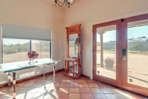 A room with a glass table, a wooden chair, a mirror, and a sliding glass door leading outside. - Pool & Views! Luxury Sonoran Desert Oasis Retreat (Tucson)
