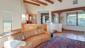 A spacious living room with a leather sofa, a patterned rug, wooden beams, and large windows. - Pool & Views! Luxury Sonoran Desert Oasis Retreat (Tucson)