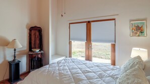 A bedroom with a bed, a nightstand, a lamp, a wooden cabinet, and a window with blinds. - Pool & Views! Luxury Sonoran Desert Oasis Retreat (Tucson)