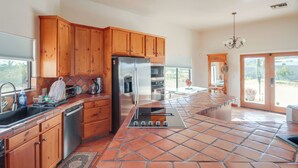 A kitchen with wooden cabinets, a stainless steel refrigerator, a built-in oven, and a tiled floor. - Pool & Views! Luxury Sonoran Desert Oasis Retreat (Tucson)