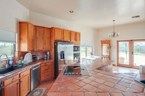 A kitchen with wooden cabinets, a stainless steel refrigerator, a built-in oven, and a tiled floor. - Pool & Views! Luxury Sonoran Desert Oasis Retreat (Tucson)