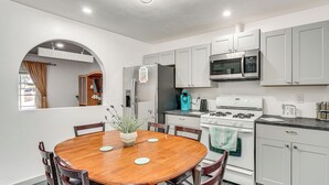 A modern kitchen with white cabinets, a stainless steel refrigerator, a microwave, a stove, and a dining table with chairs. - Patio w/ Garden Views! Tranquil Tucson Townhome (Tucson)