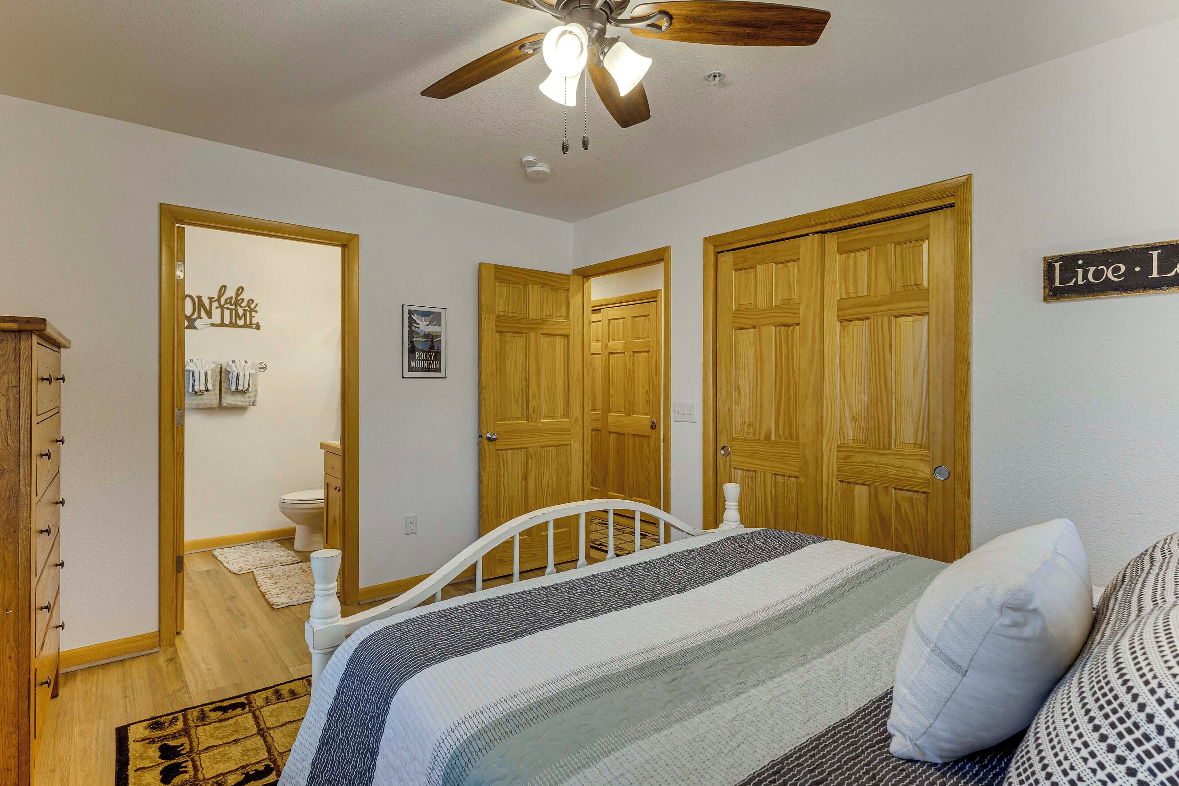 A bedroom with a bed, wooden doors, a ceiling fan, and a sign on the wall.