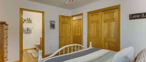 A bedroom with a bed, wooden doors, a ceiling fan, and a sign on the wall.
