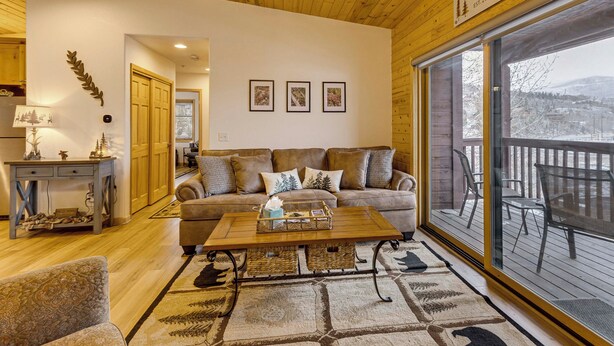 A cozy living room with a wooden ceiling, a large window, and a view of the outdoors. - Rocky Mtn-view Retreat! Walk to Dtwn Grand Lake (Grand Lake)
