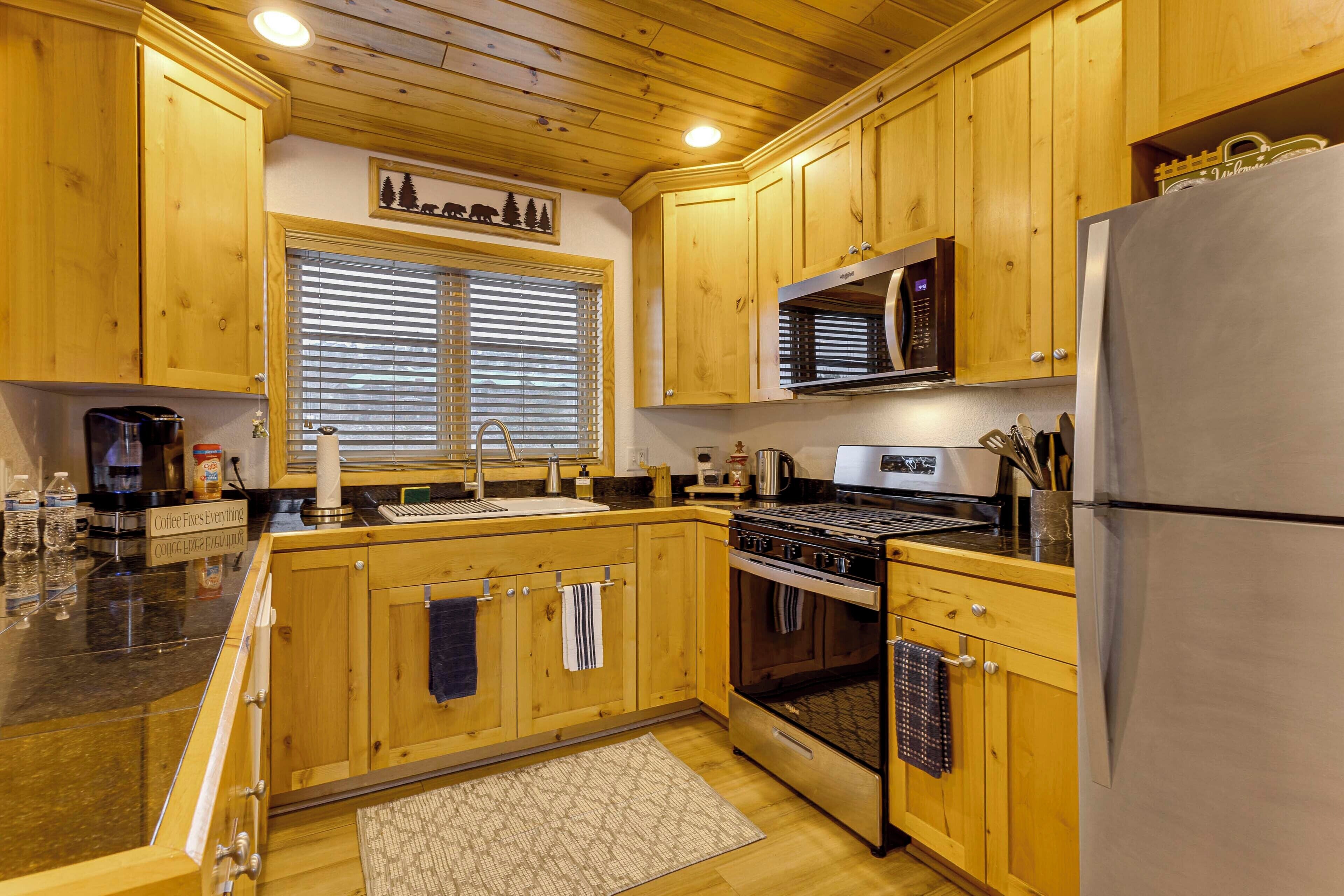 A kitchen with wooden cabinets, a stainless steel refrigerator, a microwave, and a stove.