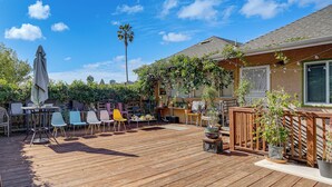 A wooden deck with outdoor furniture, potted plants, and a palm tree. - Walkable Dtwn Oakland Apt w/ Shared Rooftop! (Oakland)