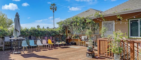 A wooden deck with outdoor furniture, potted plants, and a palm tree.