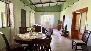 Un coin repas avec une table ronde, des chaises et un vase de fleurs.