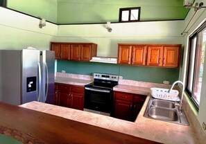 A kitchen with wooden cabinets, a stainless steel refrigerator, a stove, and a sink.