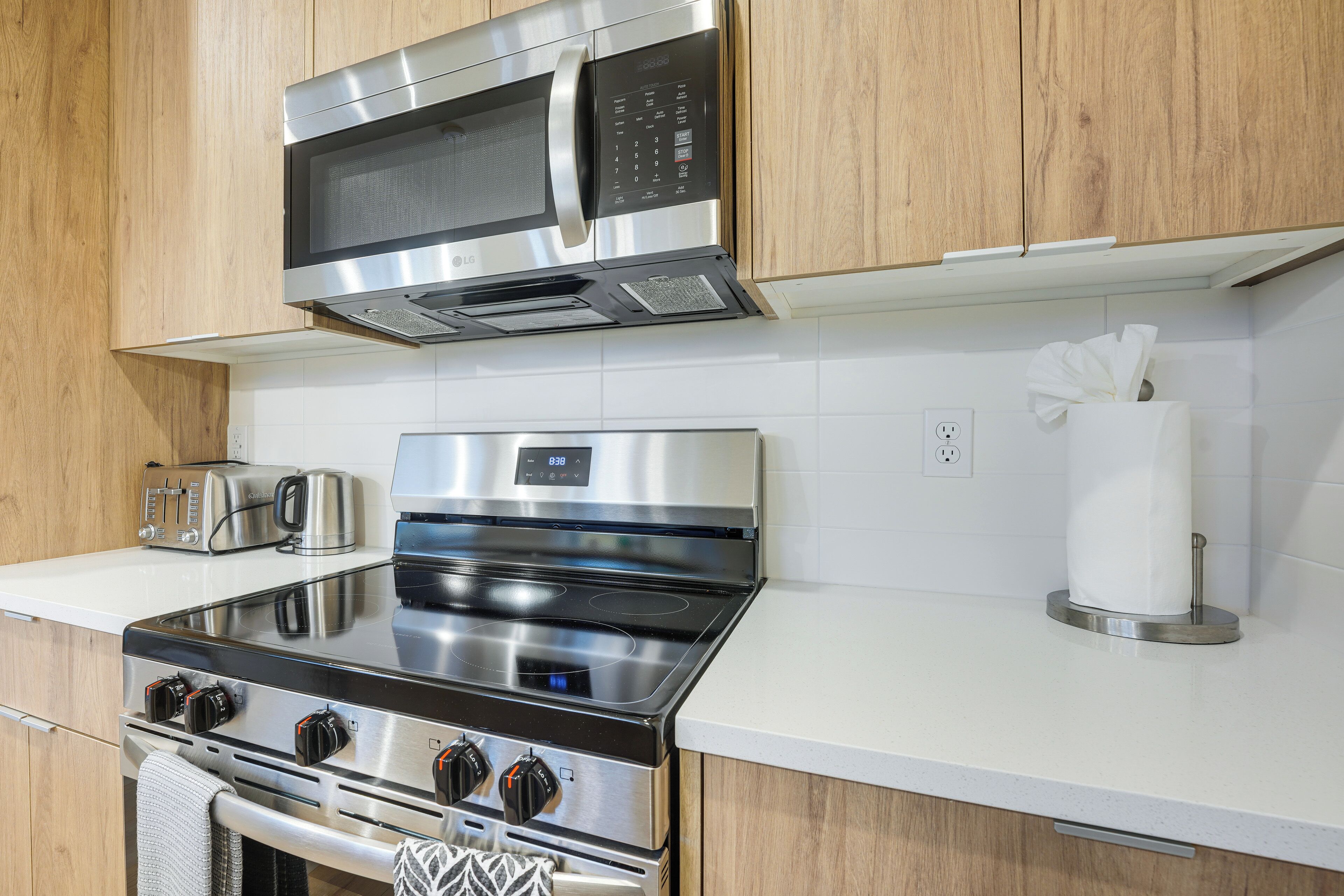 A kitchen with stainless steel appliances, a microwave, a toaster, and a paper towel holder.